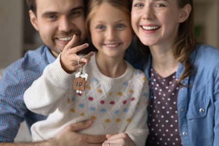 Familj som sitter tillsammans och en dotter som håller upp ett par nycklar.